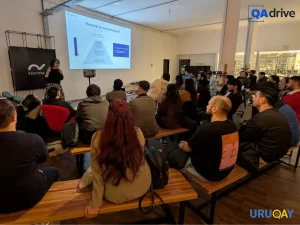 Claudia Badell presentando sobre testing colaborativo y testing ágil, acompañada por la audiencia en la meetup de UruQAy.